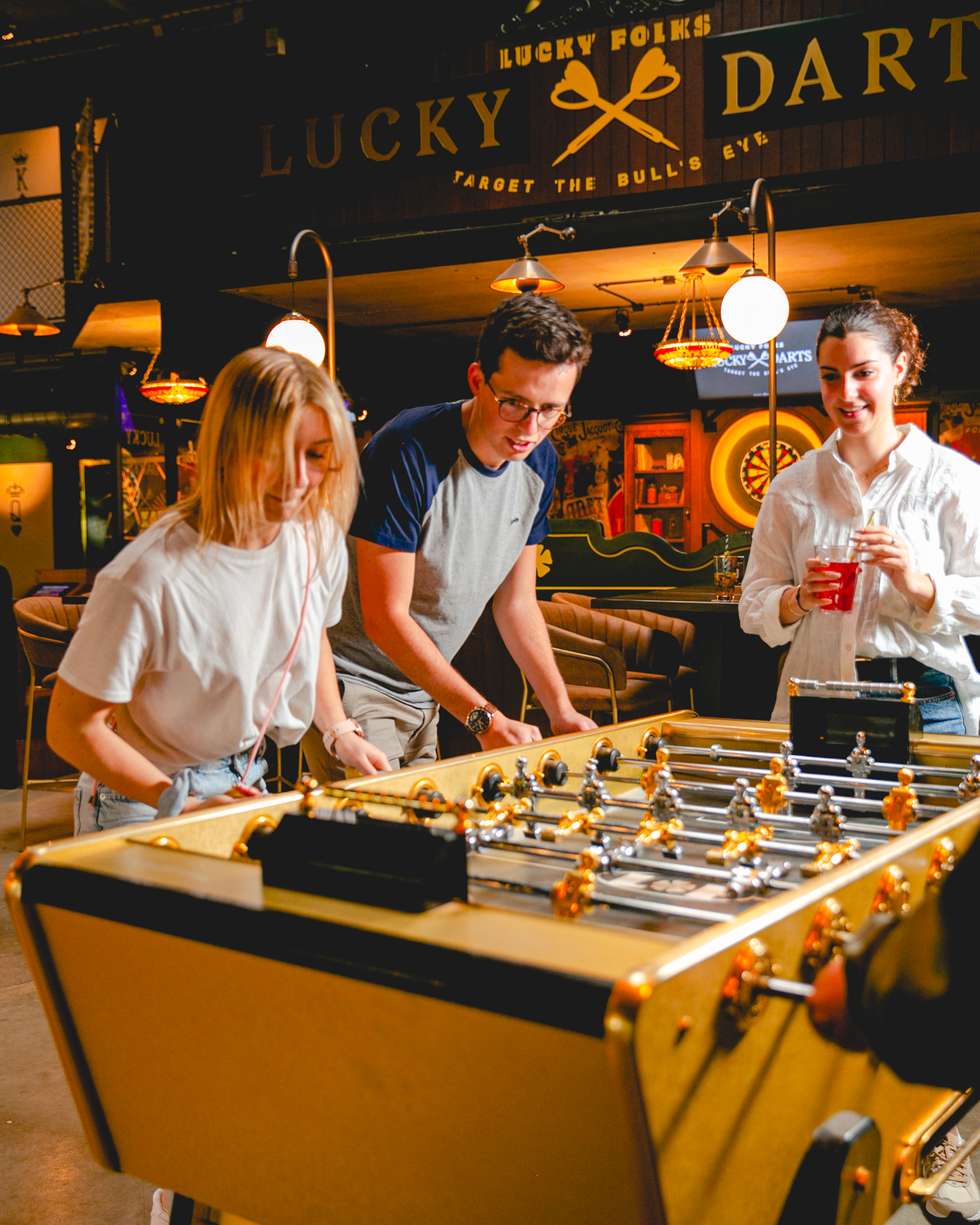 People enjoying a game on the Stella Champion Gold foosball table in a lively bar setting